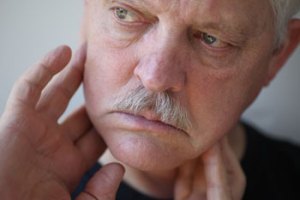 man feeling his neck / jaw area